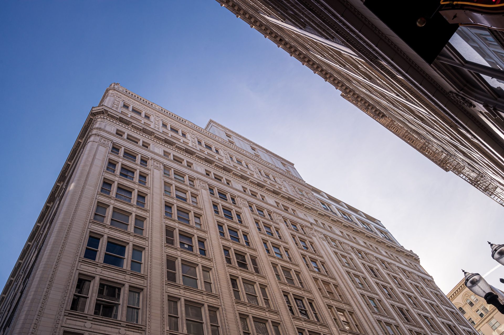 Low angle view of tall, modern urban skyscraper set against a clear blue sky, highlighting contemporary architecture.