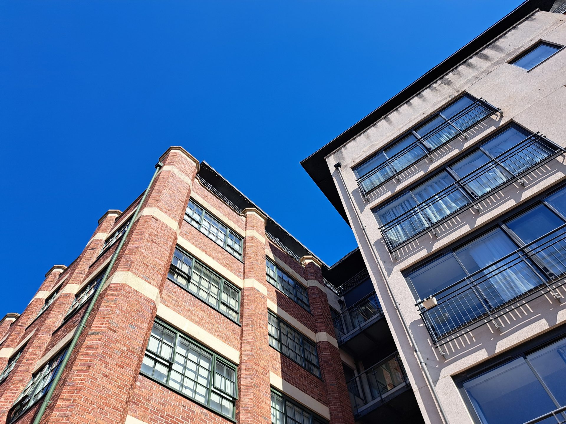 Stylish urban apartment buildings with balconies set against a clear blue sky, showcasing modern architecture.